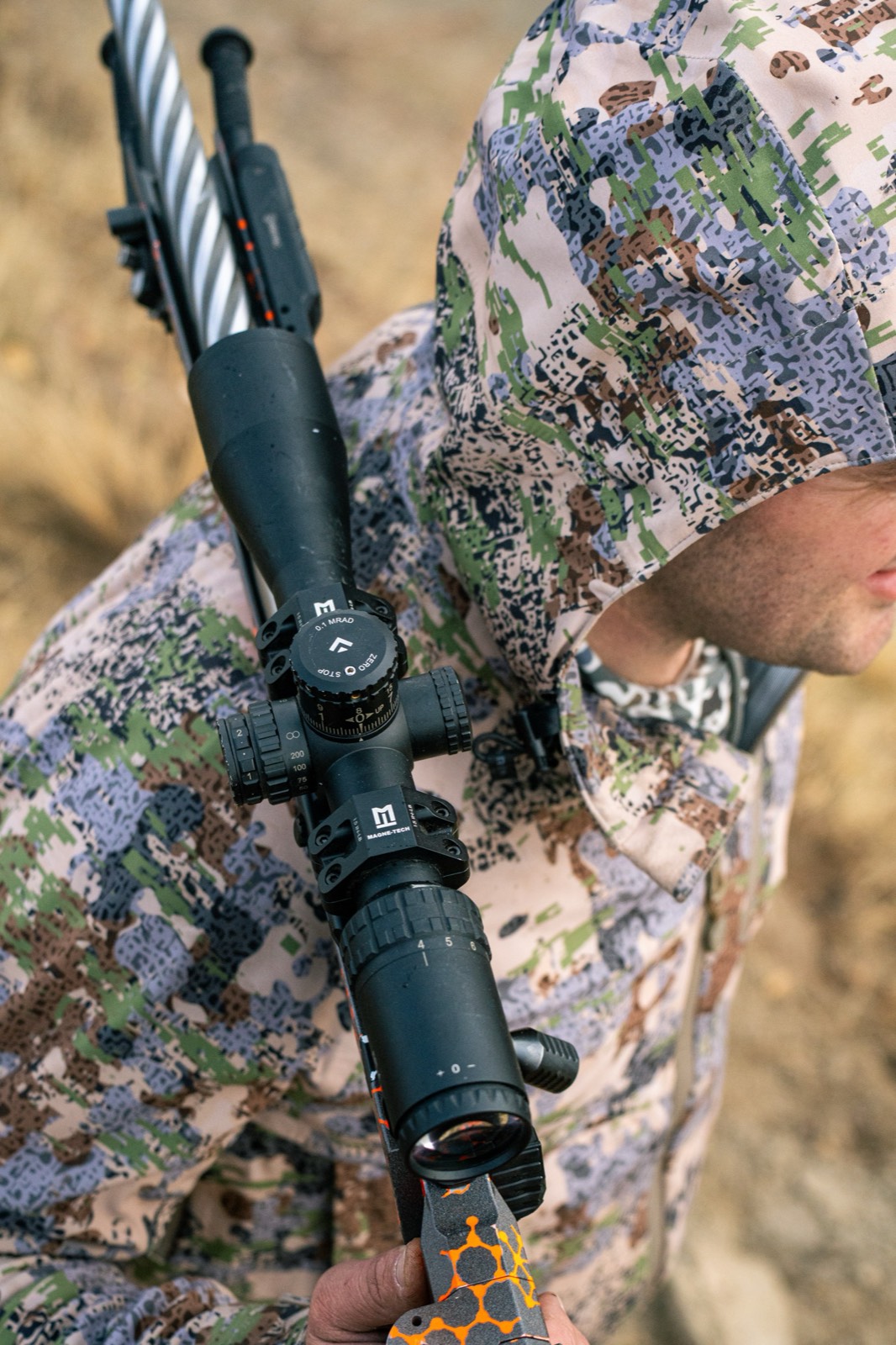 Hunter in camo carrying a scoped rifle