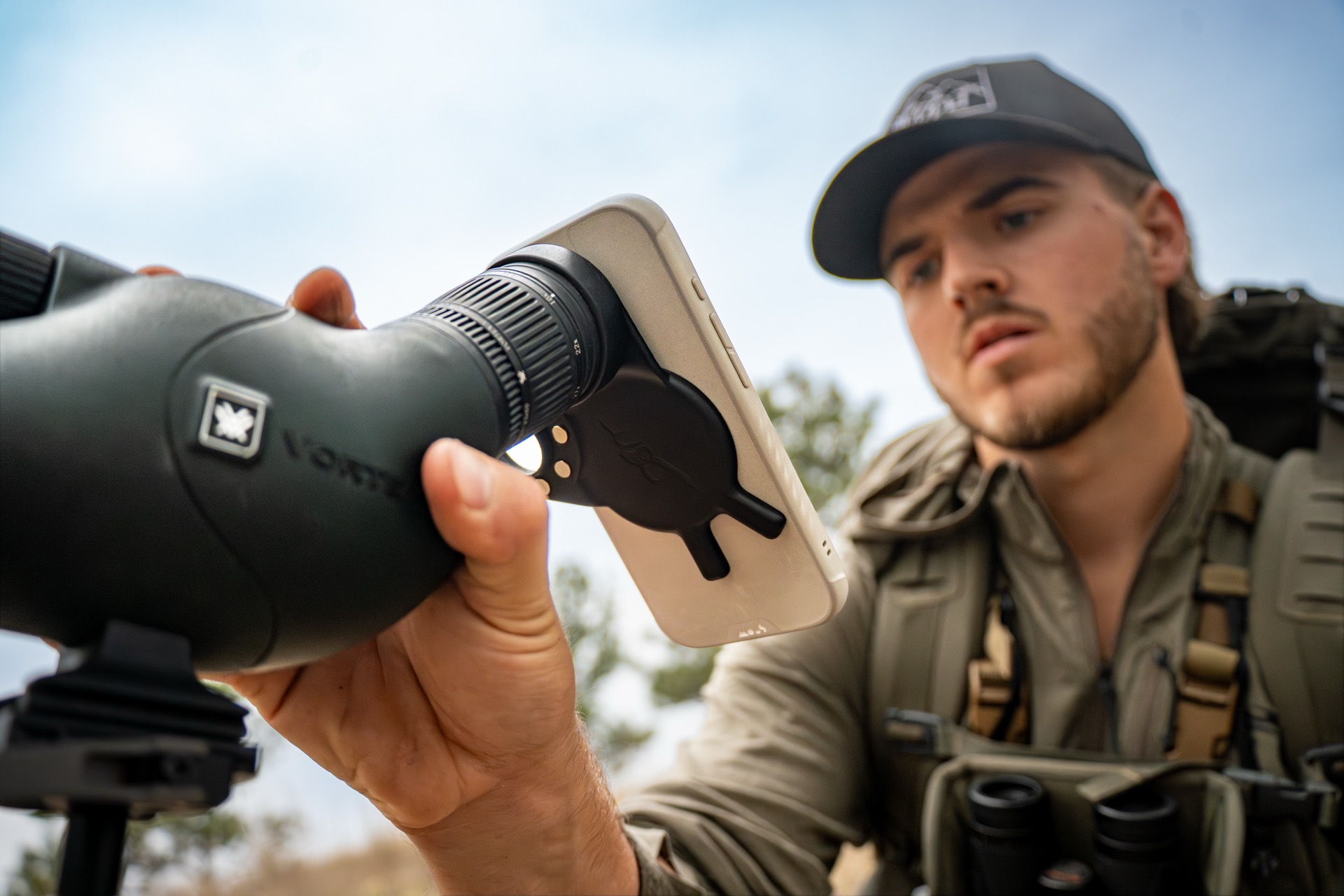 Hunter attaching a phone to a spotting scope in the field